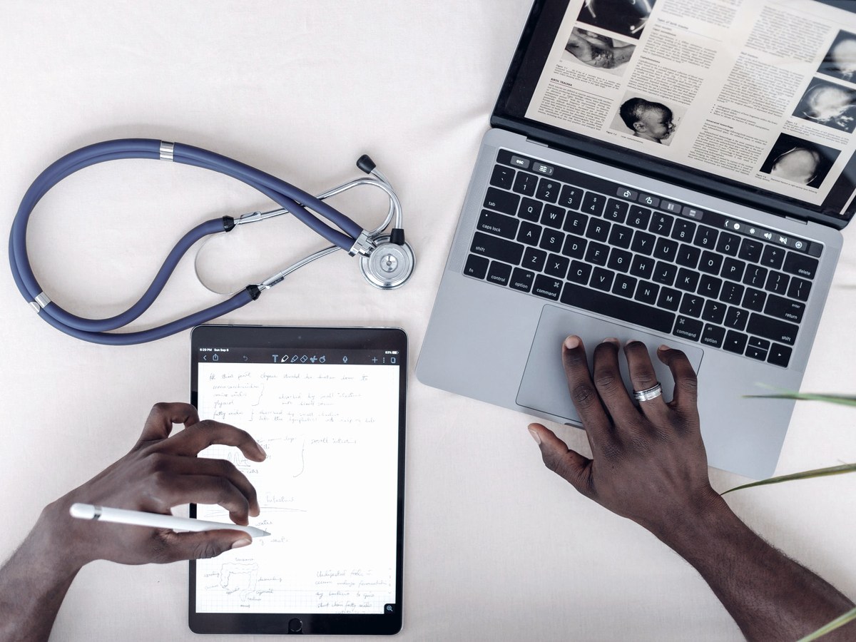 Clinical notes on a tablet beside a laptop